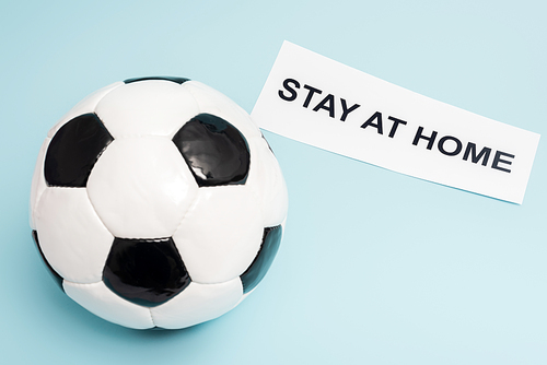 soccer ball near paper with stay at home lettering on blue