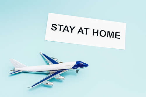 toy plane near paper with stay at home lettering on blue