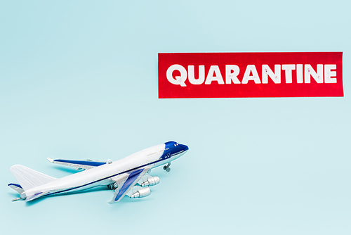 toy plane near paper with quarantine lettering isolated on blue