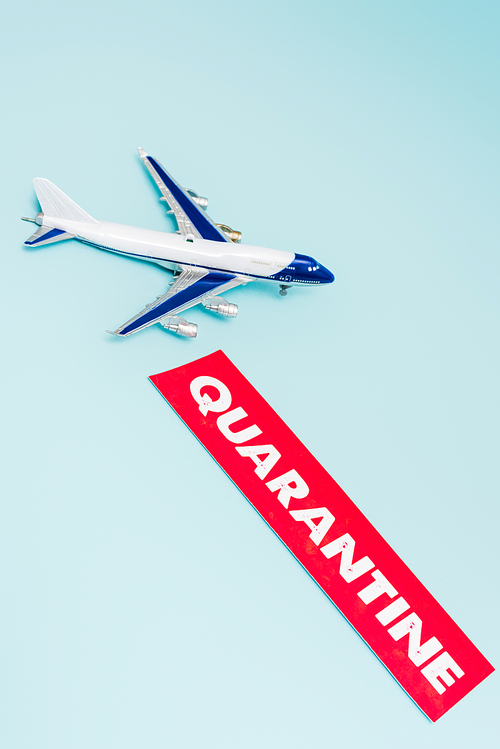 small toy plane near paper with quarantine lettering isolated on blue