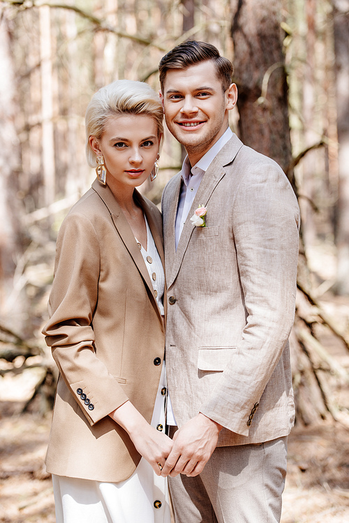 Trendy and beautiful couple holding hands in forest