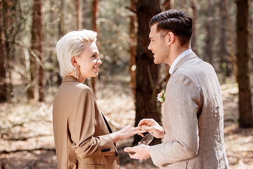 Side view of smiling man proposing to woman in forest