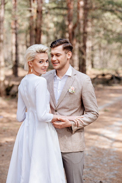 just married couple in formal wear embracing in forest