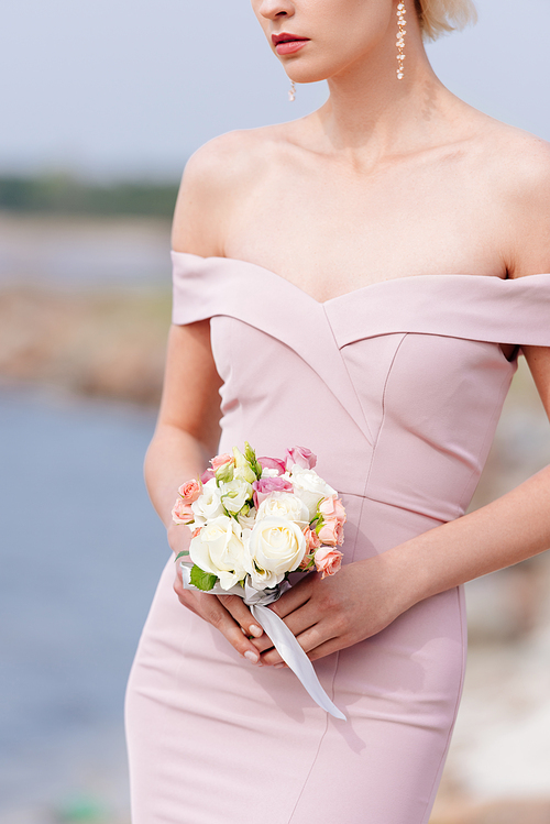 cropped view of elegant woman in pink dress holding bouquet