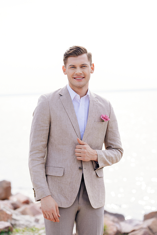 happy bridegroom in formal wear with boutonniere  with smile