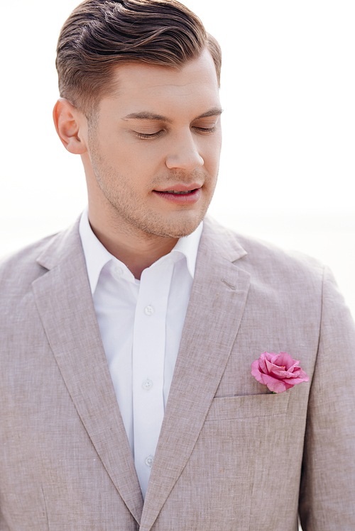 pensive bridegroom in formal wear with boutonniere with closed eyes