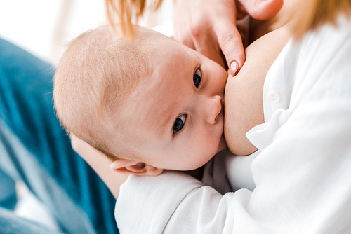 partial view of woman breastfeeding baby at home