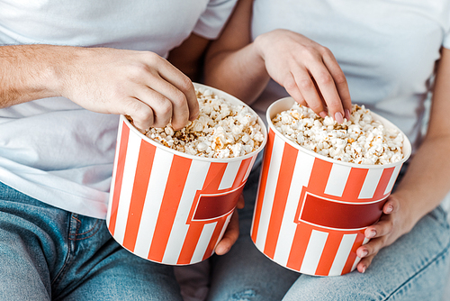 partial view of couple in jeans with popcorn