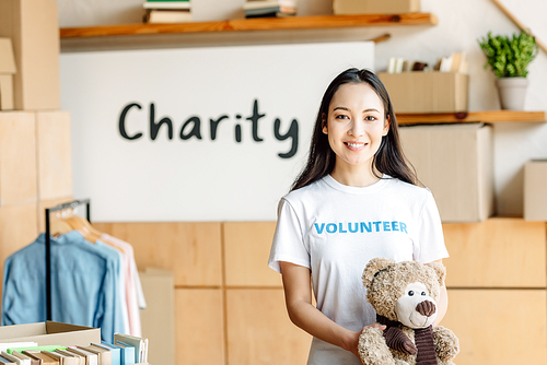 beautiful asian volunteer girl with teddy bear smiling and 