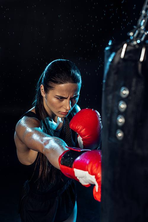 High angle view of pensive boxer in red boxing gloves training under water drops on black