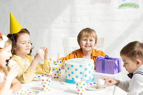 adorable kids sitting at table with cake during birthday party celebration