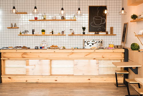 interior of cafeteria with wooden bar counter, shelves and board with drawn coffee cup