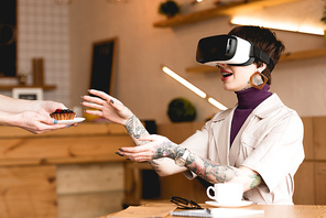 smiling businesswoman in virtual reality headset taking saucer with cake from waitress