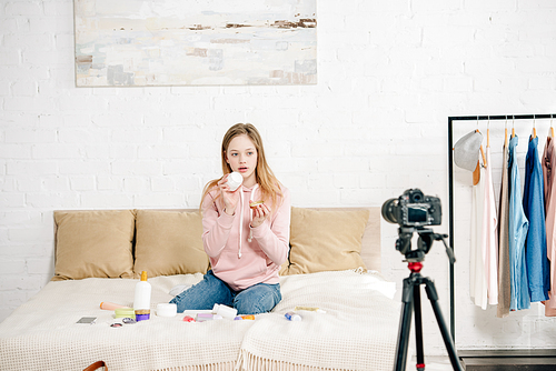 teenage . sitting on bed and showing beauty products to camera