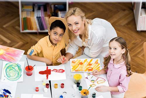 overhead view of cheerful teacher smiling with happy multicultural kids