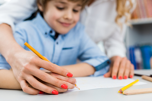 selective focus of woman drawing with happy kid