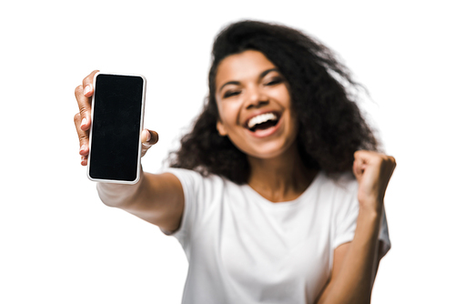selective focus of happy african american girl holding smartphone with blank screen and celebrating isolated on white