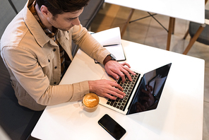 High angle view of freelancer typing on laptop keyboard in cafe