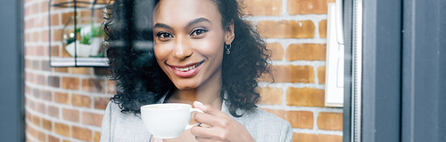 panoramic shot of african american Casual businesswoman with coffee cup behind window