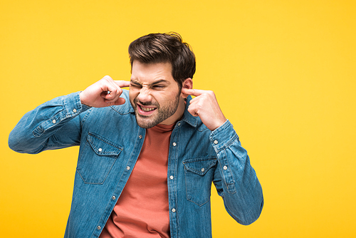 dissatisfied handsome man  ears with fingers Isolated On yellow