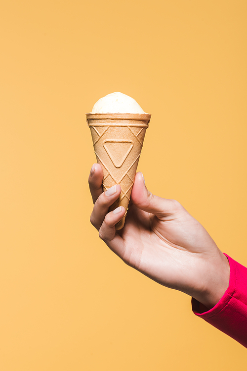 partial view of girl holding ice cream in hand, isolated on yellow