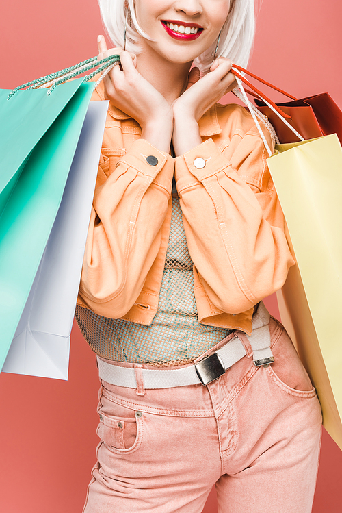 cropped view of happy girl with shopping bags, isolated on pink
