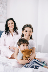 selective focus of happy kid near toddler brother and cheerful mother in bedroom