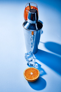 high angle view of cocktail Aperol Spritz, orange, shaker, ice cubes on blue background