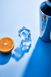 high angle view of orange, shaker, ice cubes on blue background