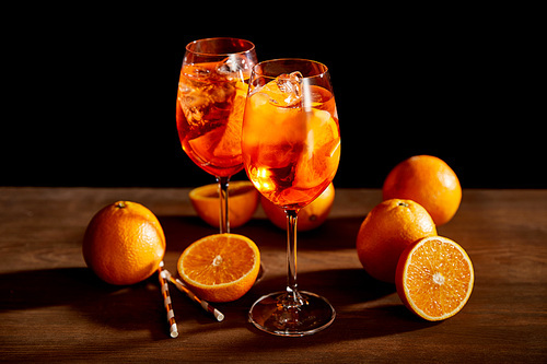Aperol Spritz in glasses and oranges on black background