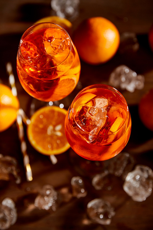 top view of Aperol Spritz in glasses, oranges and ice cubes