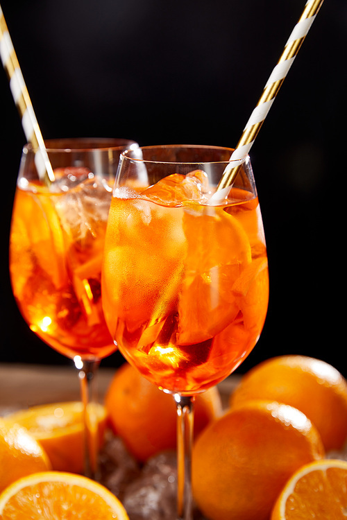 Aperol Spritz in glasses and oranges on black background