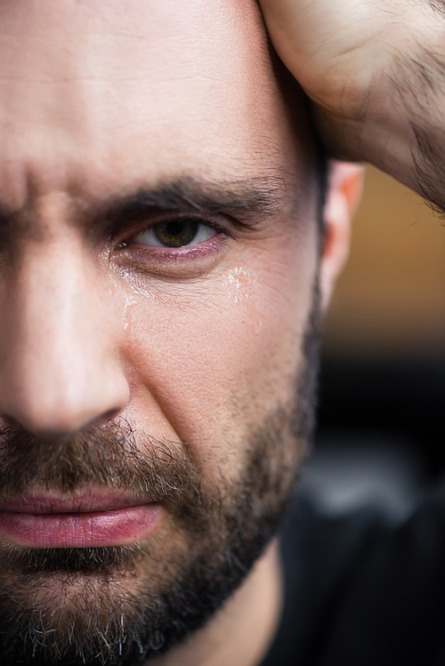 partial view of depressed bearded man crying and 