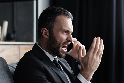 angry bearded businessman quarreling while talking on smartphone in office