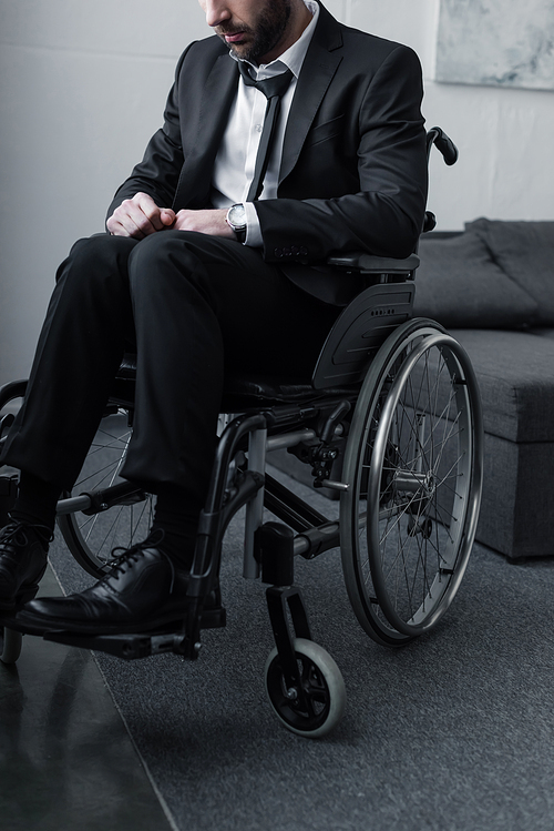 cropped view of disabled bearded man in black suit sitting in wheelchair