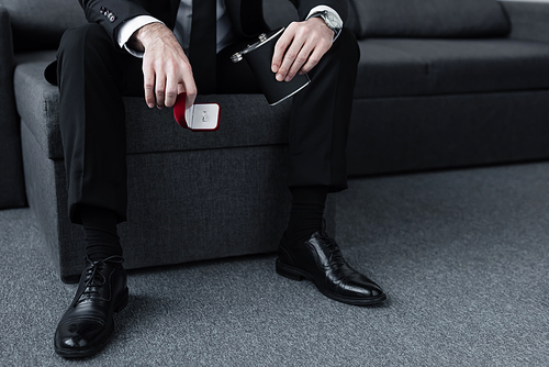 cropped view of sitting man holding flask and gift box with ring