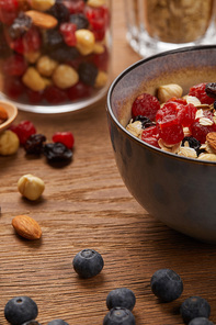 close up of berries, nuts and muesli for breakfast on wooden table