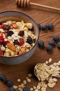 close up of berries, nuts and muesli in bowl for breakfast on wooden table