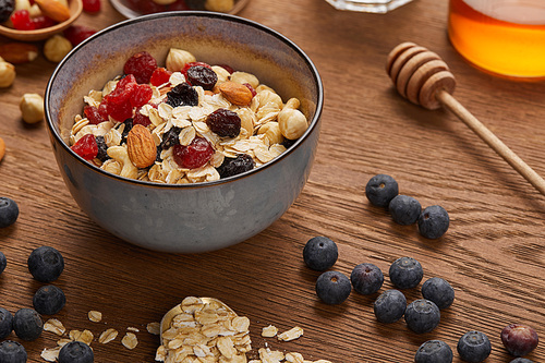 cereal in bowl with nuts and dried berries prepared for breakfast on wooden table