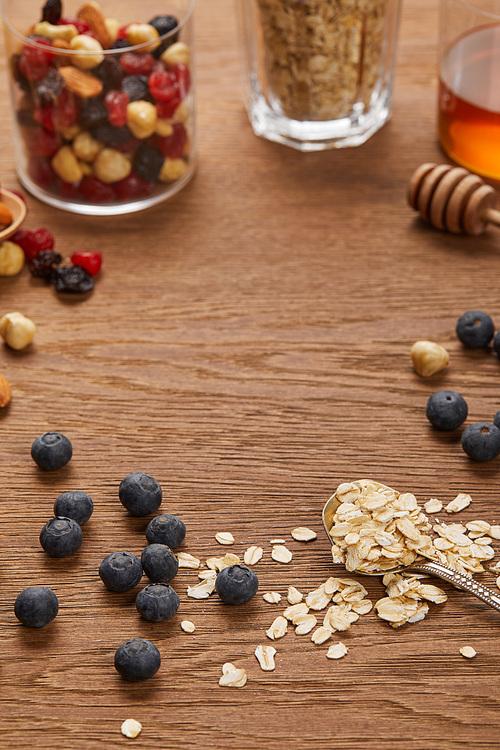 selective focus of oat flakes, nuts and dried berries on wooden table with copy space