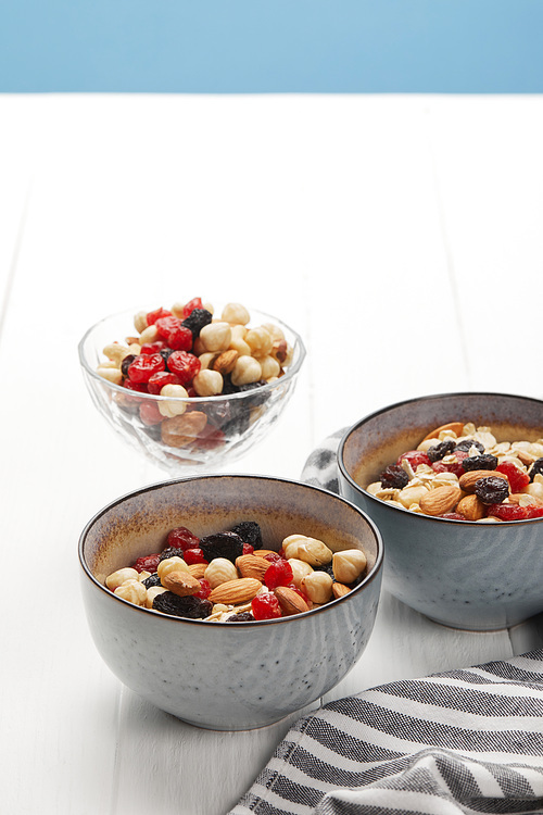 bowls with muesli, dried berries and nuts served for breakfast isolated on blue