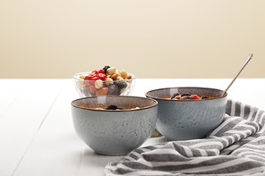 bowls with muesli, dried berries and nuts served for breakfast isolated on beige