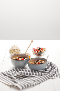 bowls with muesli, dried berries and nuts served for breakfast with honey isolated on grey