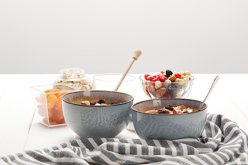 bowls with muesli, dried berries and nuts served for breakfast with dried apricots isolated on grey