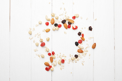 top view of scattered dried berries, oat flakes and nuts on white wooden table