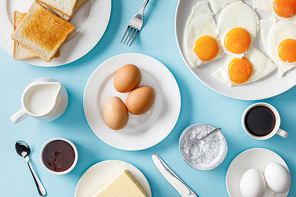 top view of served breakfast with boiled and fried eggs on blue background