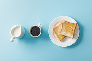 top view of milk, two toasts on white plate and cup of coffee on blue background