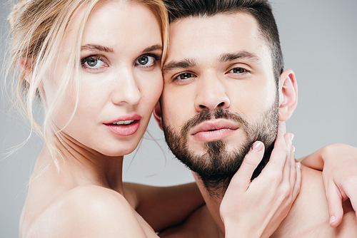 close up of nude young woman touching face of handsome bearded man on grey