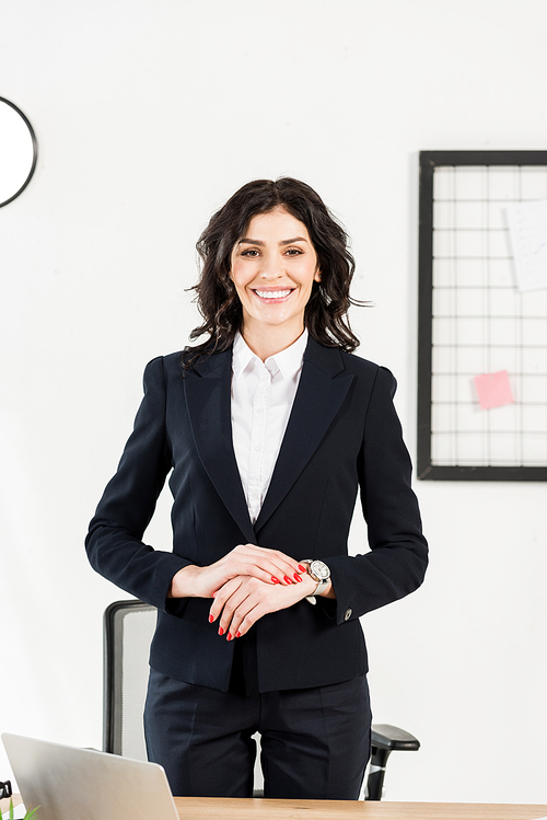 cheerful recruiter standing with clenched hands in office
