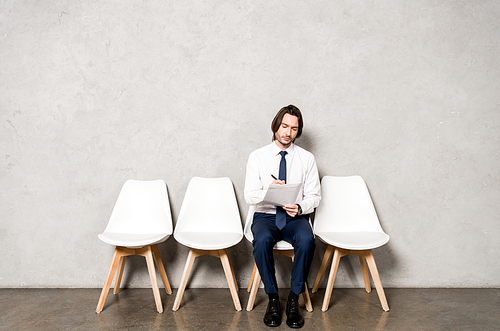 handsome man sitting on chair while waiting job interview in office